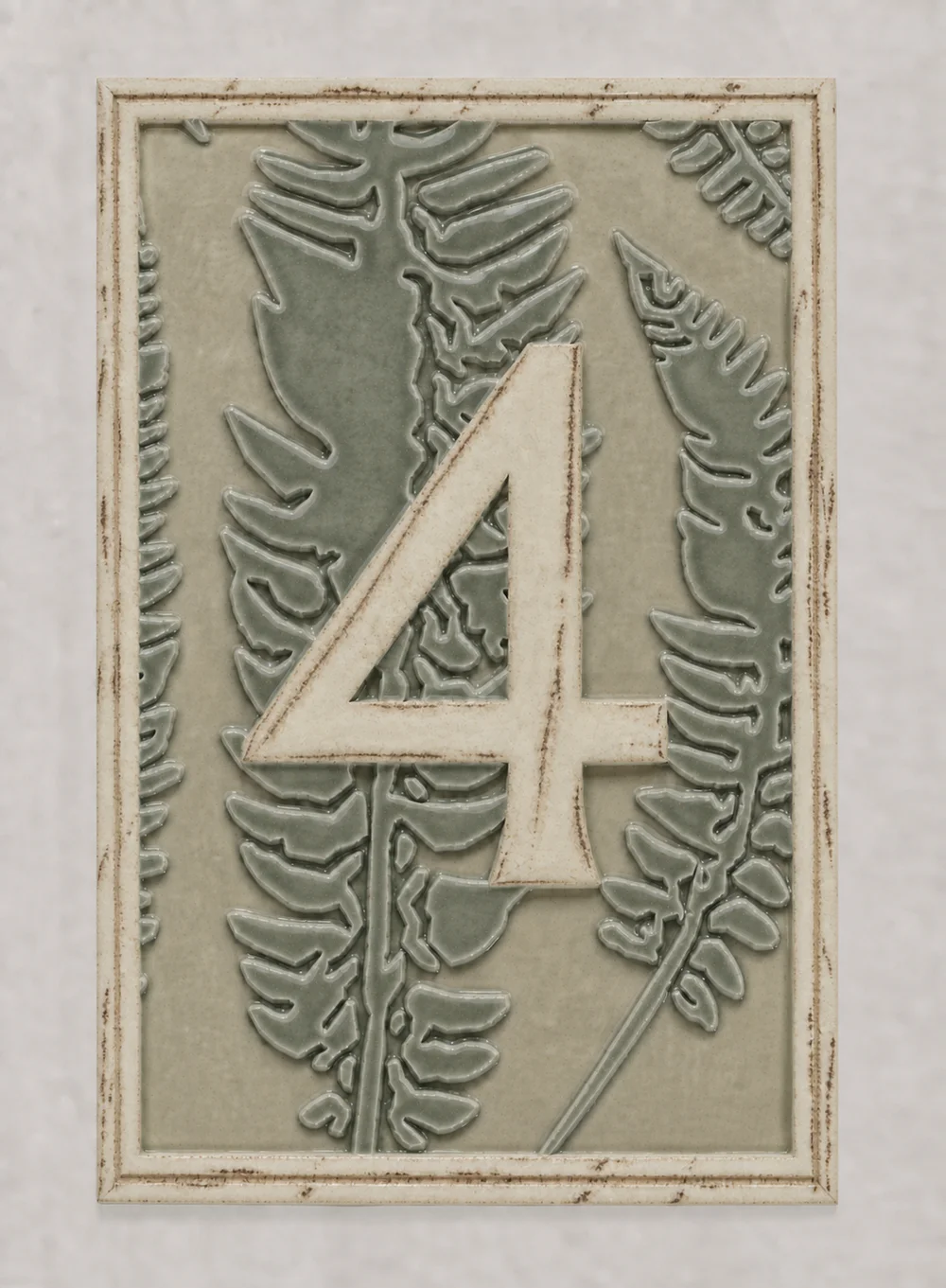 Design mockup of table number 4 with a pale yellow-salt number and double border against green celadon ferns.