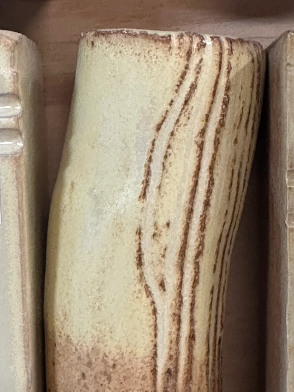Yellow-salt test tile with a pale creamy surface and brown showing through its grooves.